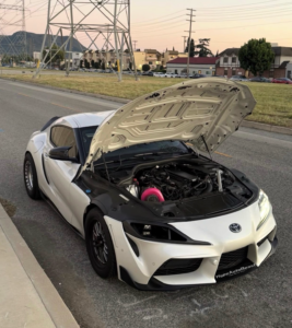 White Toyota Supra A91 engine bay view featuring carbon fiber headlight intake vent