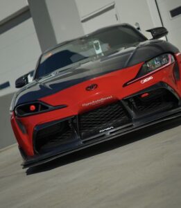 Red and black Toyota Supra A90 front bumper with carbon fiber headlight vent upgrade