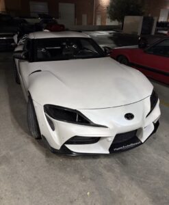 Night view of perfect fitment carbon fiber headlight air duct on white Toyota Supra